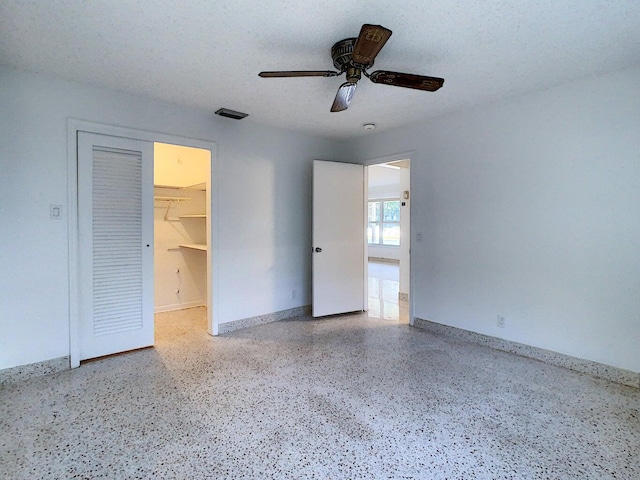 unfurnished bedroom with a spacious closet, a closet, ceiling fan, and a textured ceiling