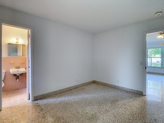 unfurnished room featuring tile walls and sink