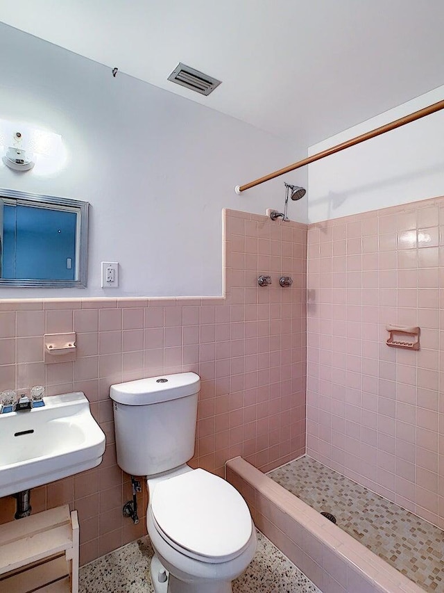 bathroom featuring tile walls, toilet, and tiled shower