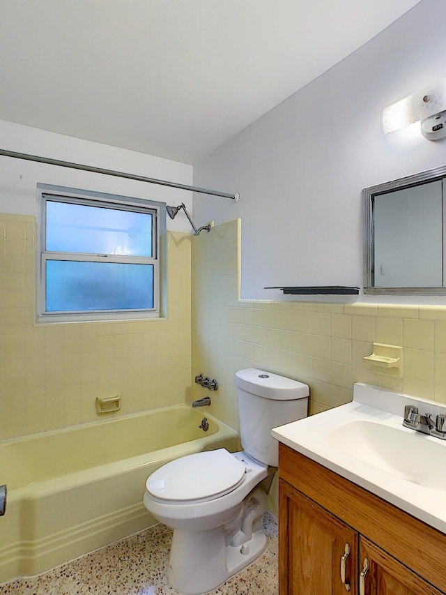 full bathroom with tile walls, vanity, toilet, and tiled shower / bath combo