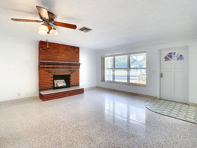 unfurnished living room featuring a textured ceiling, ceiling fan, and a brick fireplace