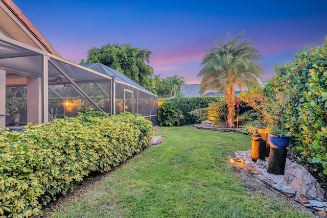 yard at dusk featuring glass enclosure