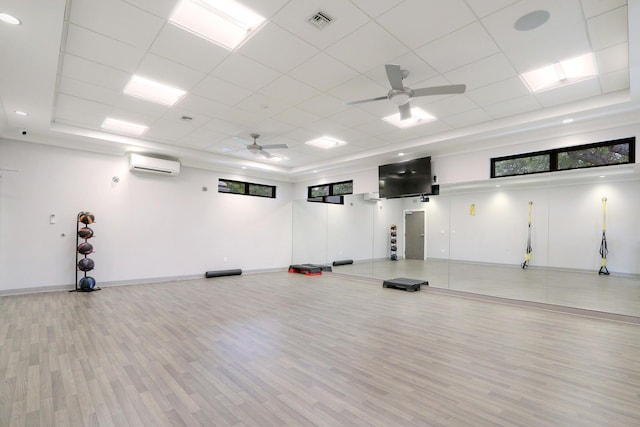 interior space with ceiling fan, light wood-type flooring, a paneled ceiling, and a wall mounted AC