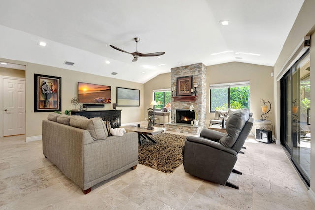 living room featuring ceiling fan, a stone fireplace, and lofted ceiling