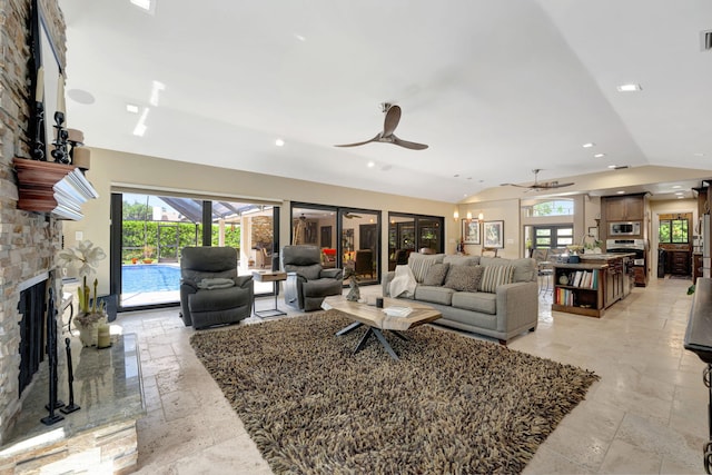 living room with a stone fireplace, lofted ceiling, and ceiling fan