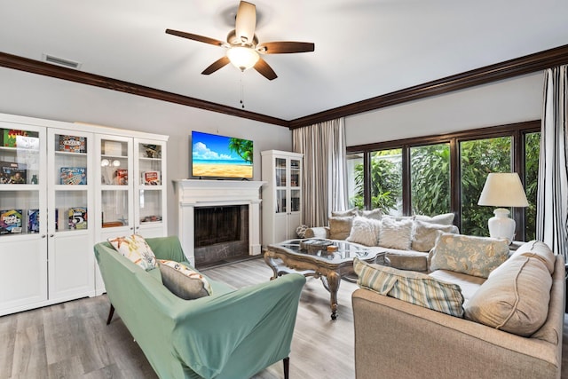 living room featuring ornamental molding, light wood-type flooring, and ceiling fan