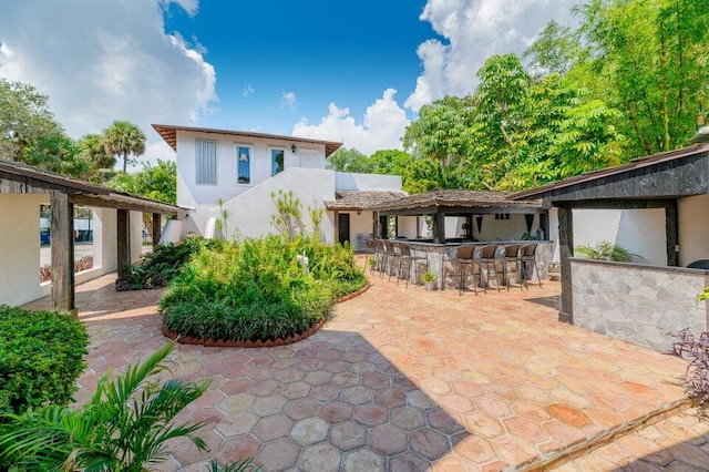 back of property with exterior bar and a patio