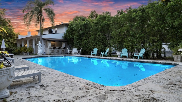 pool at dusk with a patio area