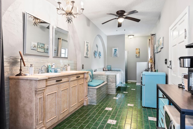 bathroom with vanity, a bathtub, a textured ceiling, and ceiling fan with notable chandelier