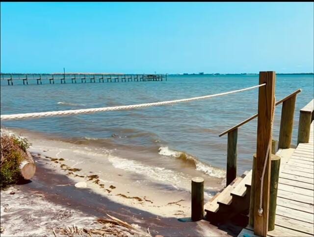 view of dock with a water view and a view of the beach