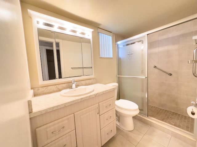 bathroom with tile patterned flooring, vanity, a shower with shower door, and toilet