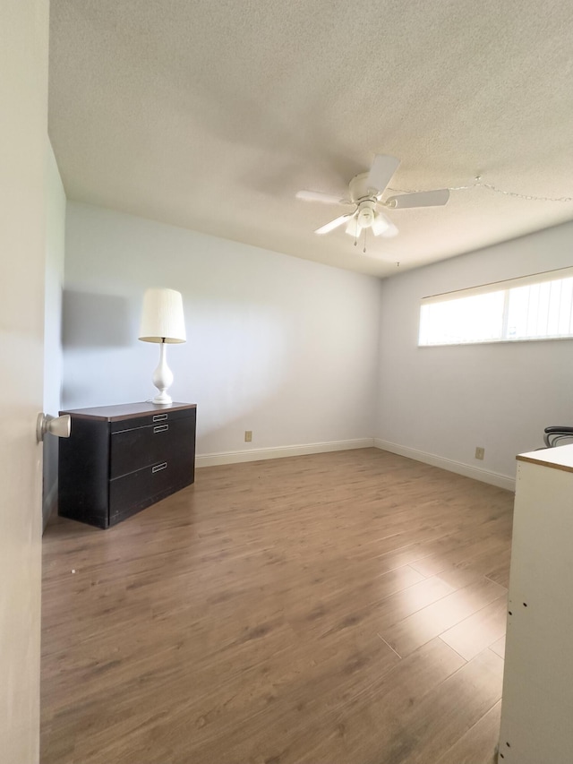 spare room with ceiling fan, wood-type flooring, and a textured ceiling