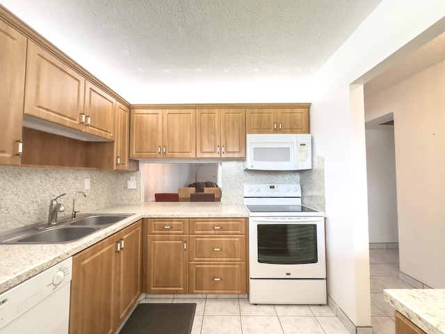 kitchen with light tile patterned flooring, a textured ceiling, white appliances, and sink