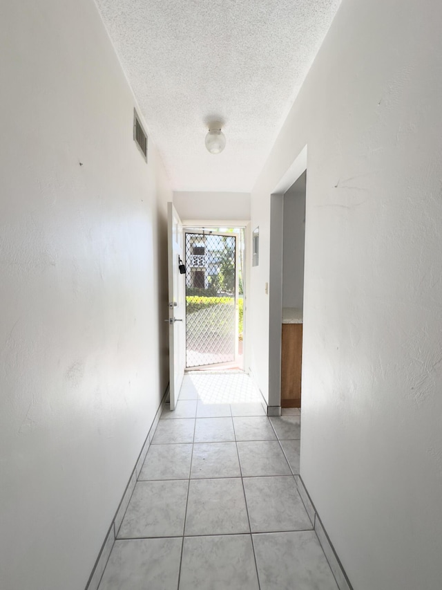 hallway with light tile patterned floors and a textured ceiling