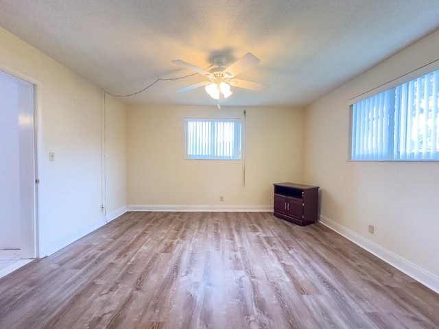 spare room with ceiling fan, light hardwood / wood-style flooring, and a textured ceiling