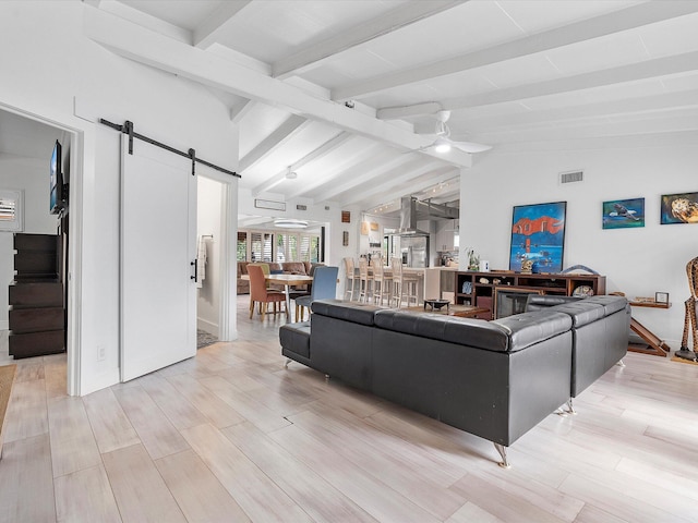 living room featuring lofted ceiling with beams, ceiling fan, a barn door, and light hardwood / wood-style floors