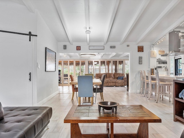 living room featuring a barn door, beamed ceiling, and light wood-type flooring