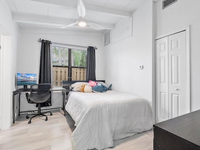 bedroom with ceiling fan, a closet, light hardwood / wood-style floors, and vaulted ceiling with beams