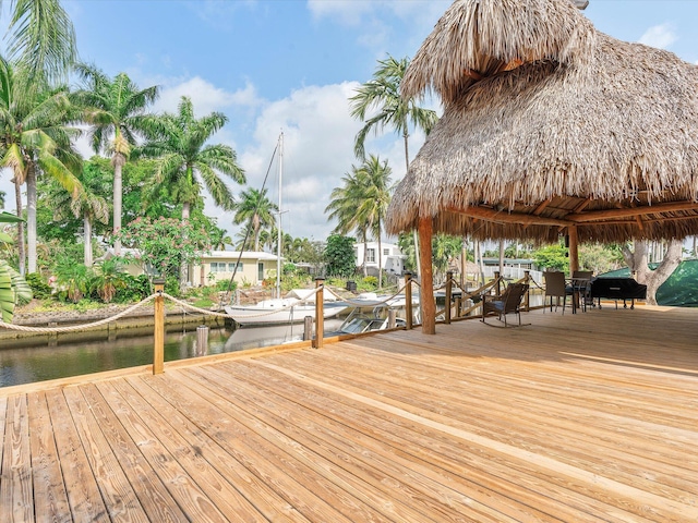 wooden terrace featuring a dock, a grill, and a water view