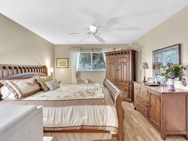 bedroom with light wood-style flooring, a textured ceiling, and a ceiling fan