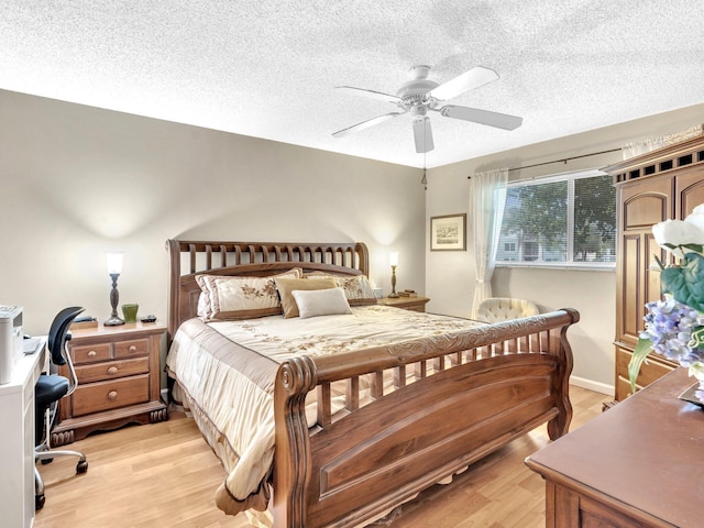 bedroom featuring ceiling fan, light wood-style floors, baseboards, and a textured ceiling