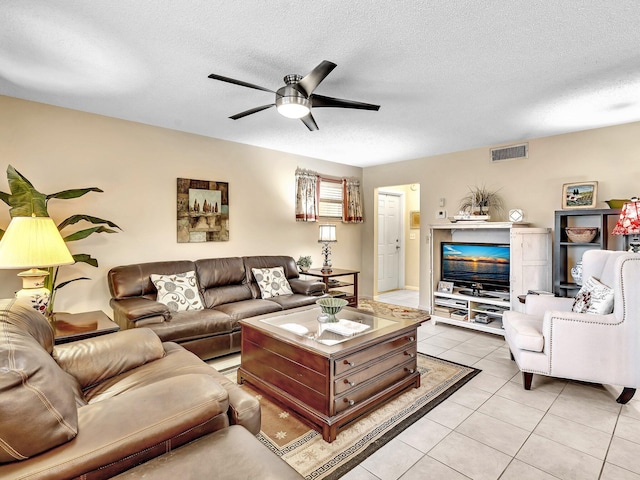 living room with light tile patterned floors, visible vents, a textured ceiling, and ceiling fan