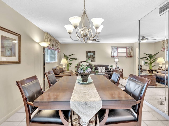 tiled dining space with ceiling fan with notable chandelier and a textured ceiling