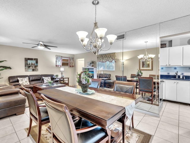 dining space with light tile patterned floors, visible vents, ceiling fan with notable chandelier, and a textured ceiling