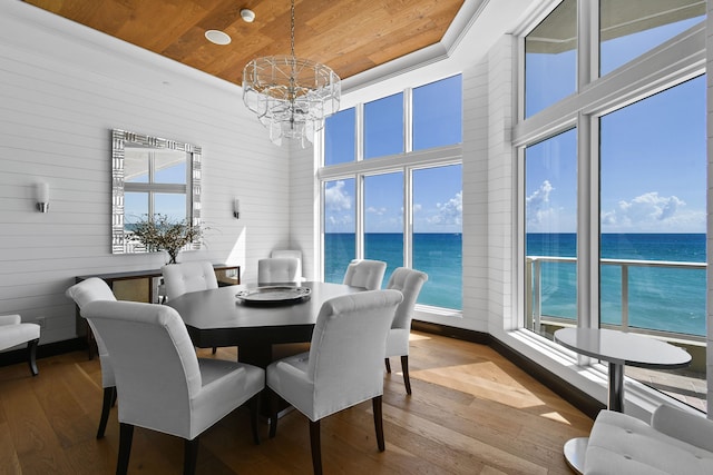 dining area with wood walls, a chandelier, a water view, wooden ceiling, and light hardwood / wood-style flooring