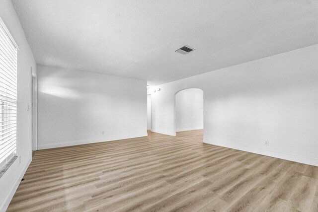 spare room with a textured ceiling and light hardwood / wood-style floors