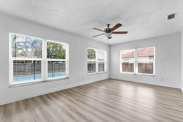 empty room featuring ceiling fan, a textured ceiling, and light hardwood / wood-style flooring