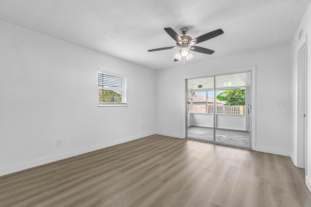 empty room with ceiling fan, hardwood / wood-style flooring, a textured ceiling, and a wealth of natural light