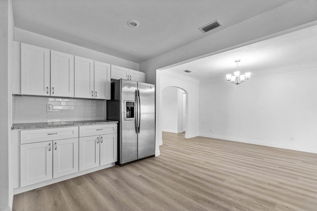 kitchen featuring light hardwood / wood-style floors, stainless steel fridge with ice dispenser, white cabinetry, an inviting chandelier, and backsplash