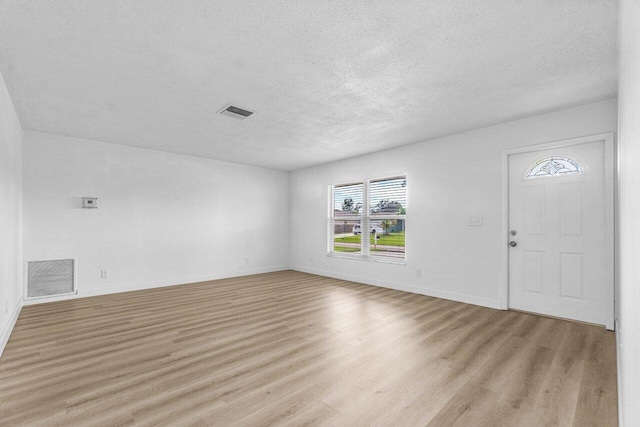 unfurnished living room with a textured ceiling and light wood-type flooring