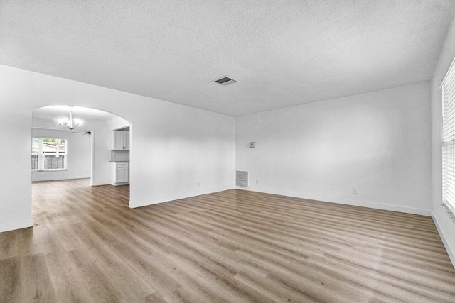 unfurnished room with a textured ceiling and light hardwood / wood-style flooring