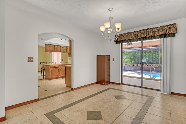 tiled empty room with an inviting chandelier and a textured ceiling