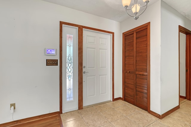 tiled entrance foyer with an inviting chandelier and a textured ceiling