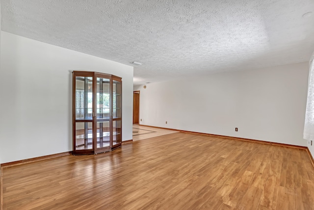 spare room with light wood-type flooring and a textured ceiling