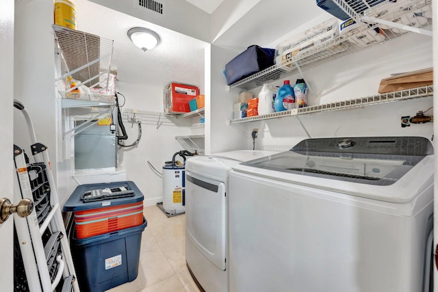 laundry room with washer and clothes dryer, light tile patterned floors, and water heater