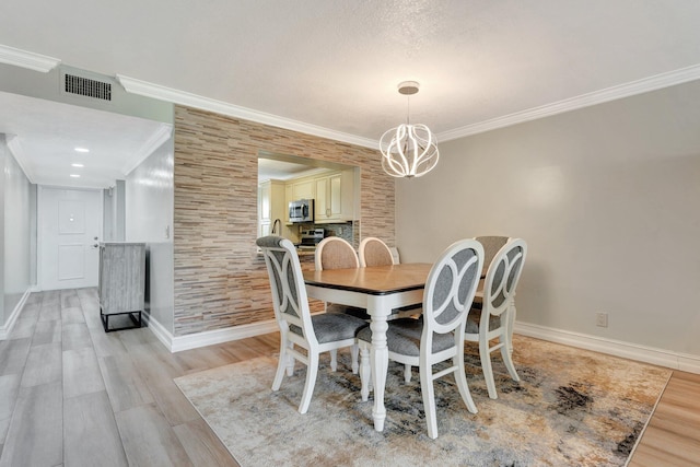 dining space featuring light hardwood / wood-style flooring, ornamental molding, and an inviting chandelier