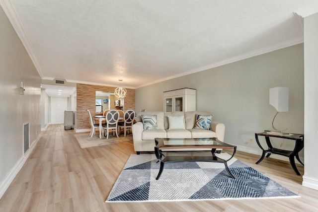 living room featuring brick wall, a textured ceiling, light hardwood / wood-style flooring, and crown molding