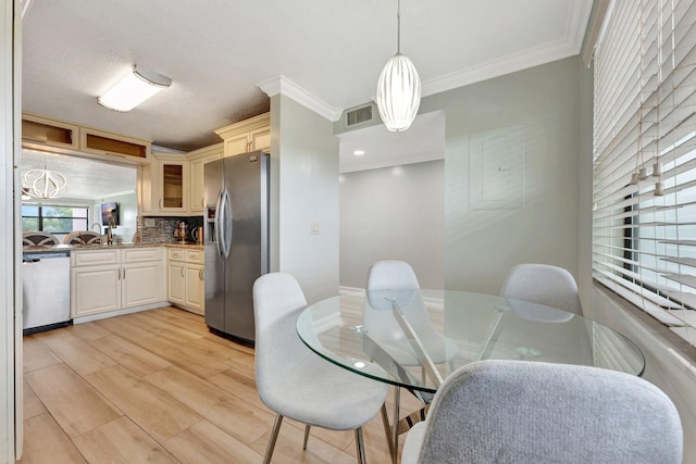 dining room with sink, crown molding, and light hardwood / wood-style floors