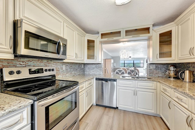 kitchen featuring light hardwood / wood-style floors, sink, stainless steel appliances, backsplash, and light stone countertops