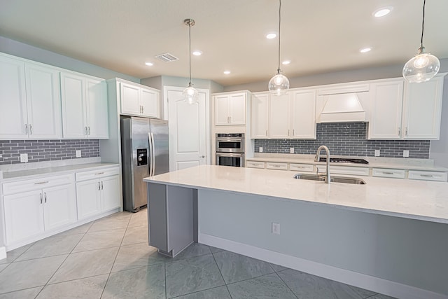 kitchen with light stone countertops, white cabinetry, stainless steel appliances, pendant lighting, and premium range hood