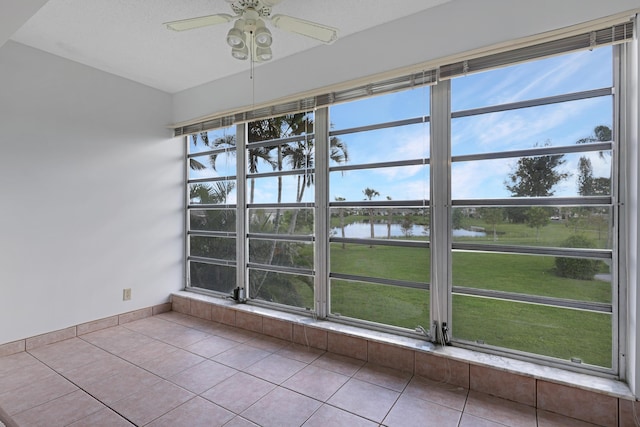 interior space featuring light tile patterned floors, a water view, and ceiling fan