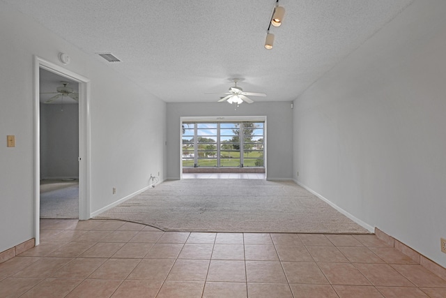 spare room featuring a textured ceiling, ceiling fan, and light tile patterned flooring