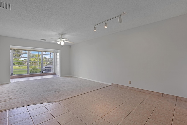 carpeted empty room featuring ceiling fan, track lighting, and a textured ceiling