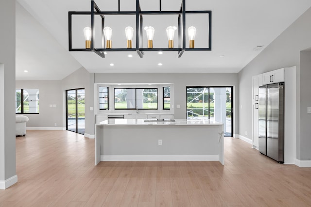 kitchen featuring a wealth of natural light, white cabinetry, light wood-type flooring, and stainless steel fridge