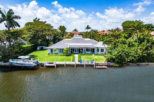 back of house with a lawn and a water view