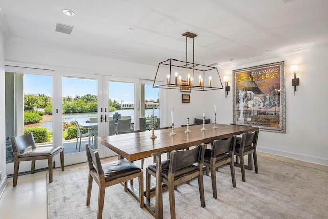 dining room with an inviting chandelier, a water view, french doors, and crown molding